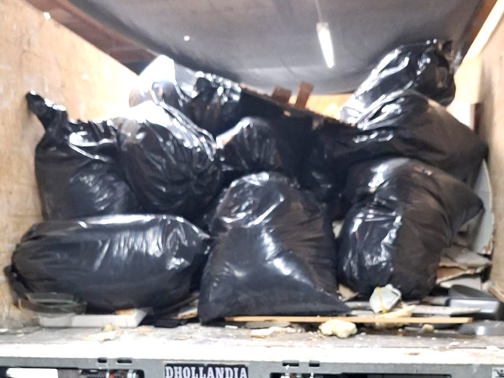 Dump truck backed into a garage, loaded with bagged junk from a cleanout